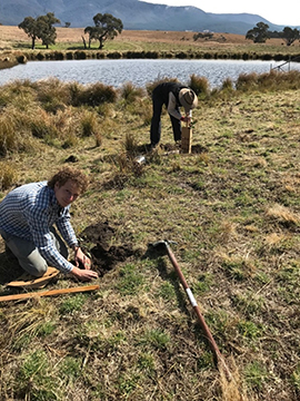 Image of two people working near a dam