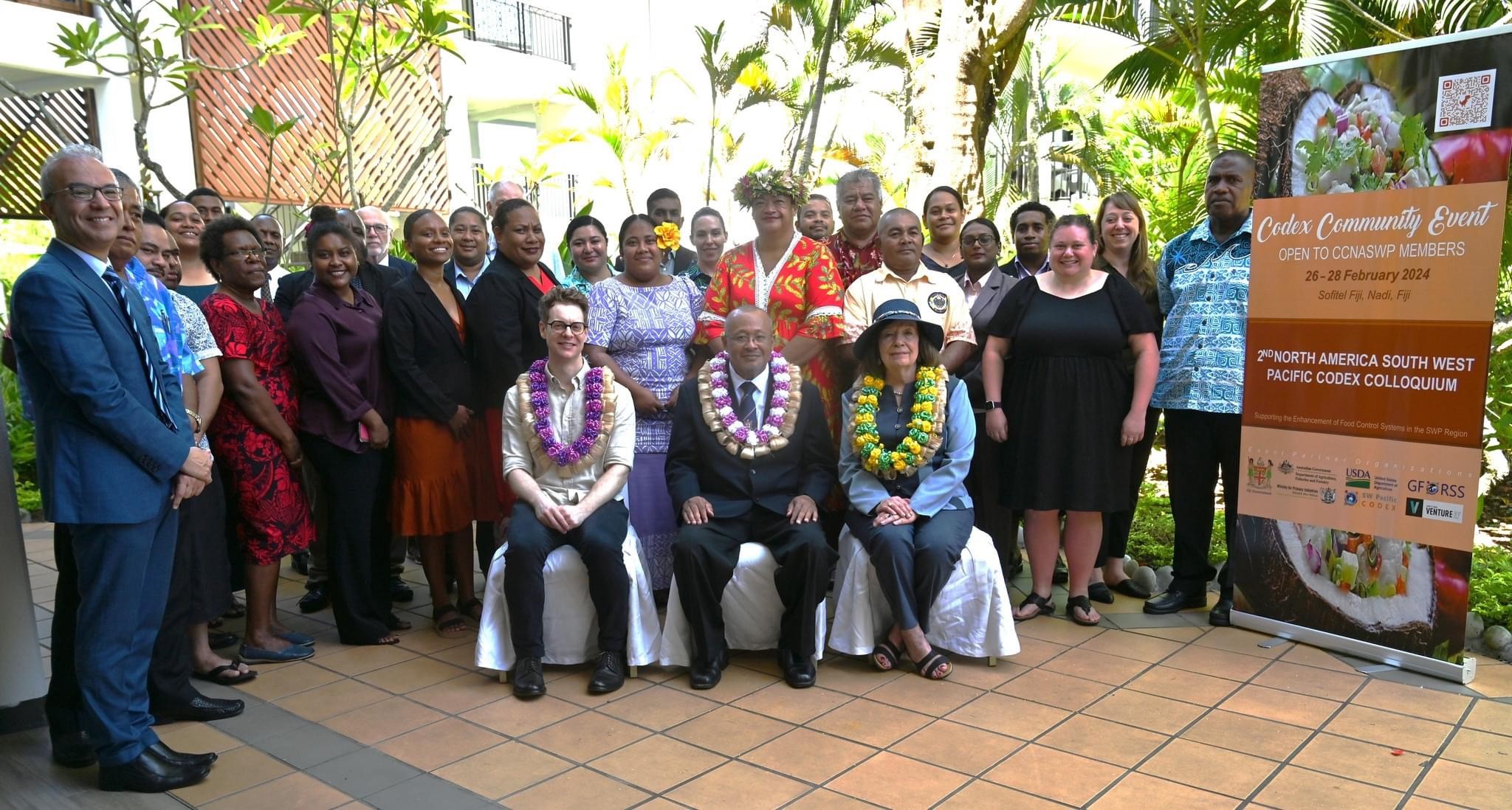 Image of a group of people, three seated, many others standing behind them. They are (seated, left to right) Scott Mersch, Director, Codex Australia, Australian Department of Agriculture, Fisheries and Forestry; Dr Andrew Tukana, Permanent Secretary, Fiji Department of Agriculture and Waterways (and Codex Regional Coordinator); and Mary Frances Lowe, Manager, United States Codex Office, US Department of Agriculture.