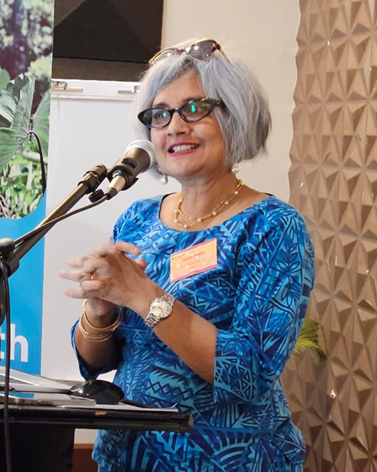 Dr. Raana standing at a microphone and podium presenting.