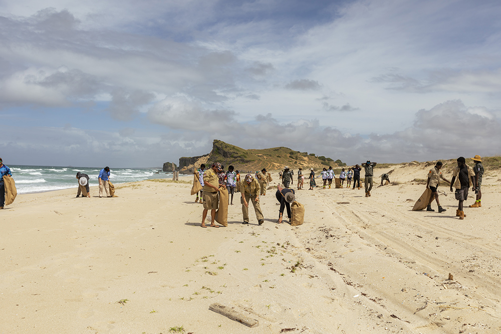 Image of several people gathering nets on a white sandy beach