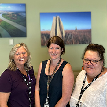 Image of three people standing, smiling at the camera - they are Dr Beth Cookson with members of the OCVO - Northern Australia team