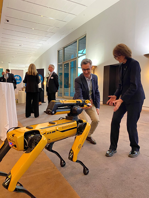 DAFF secretary, Adam Fennessy and Dr Cathy Foley making gestures in front of Spot the robotic detector dog.