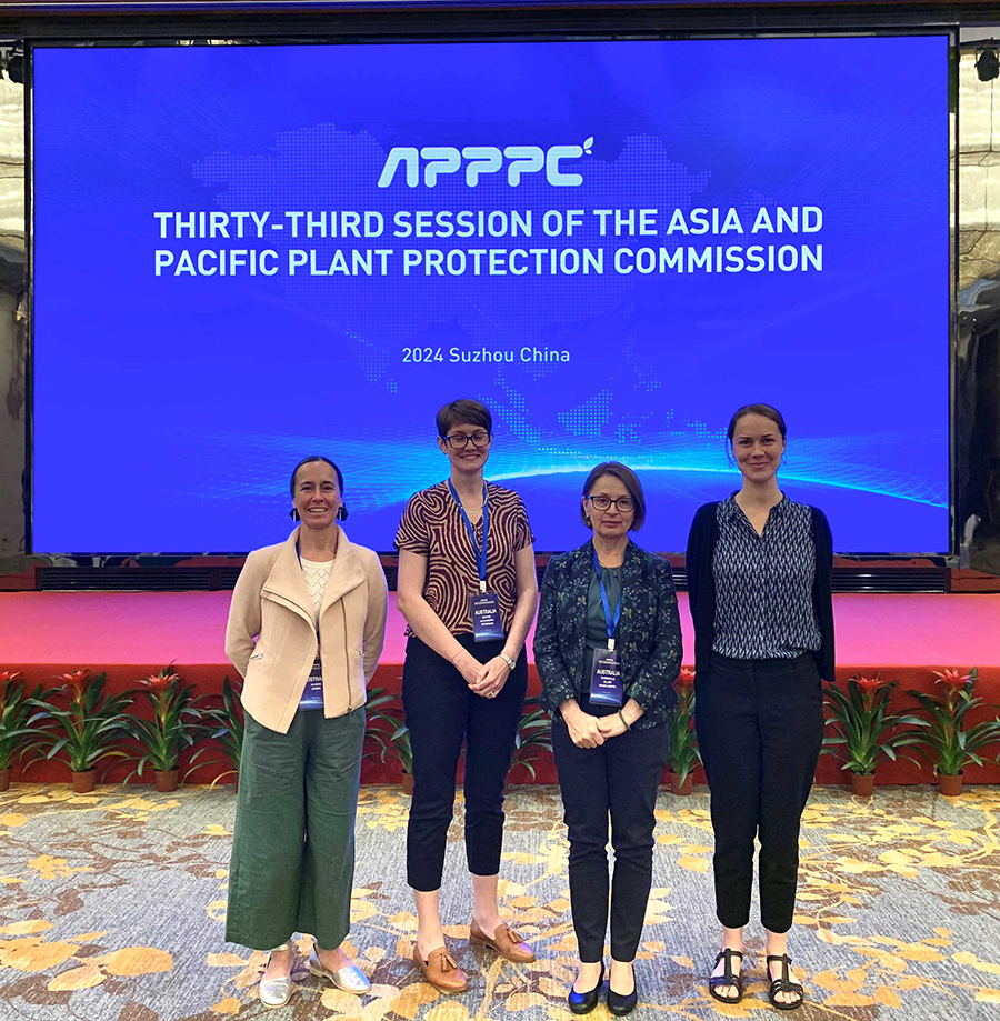 Image of four people standing in front of large screen which says Thirty-third session of the Asia and Pacific Plant Protection Commission