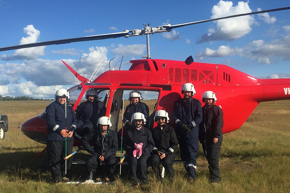 Biosecurity Queensland team in front of a red helicopter