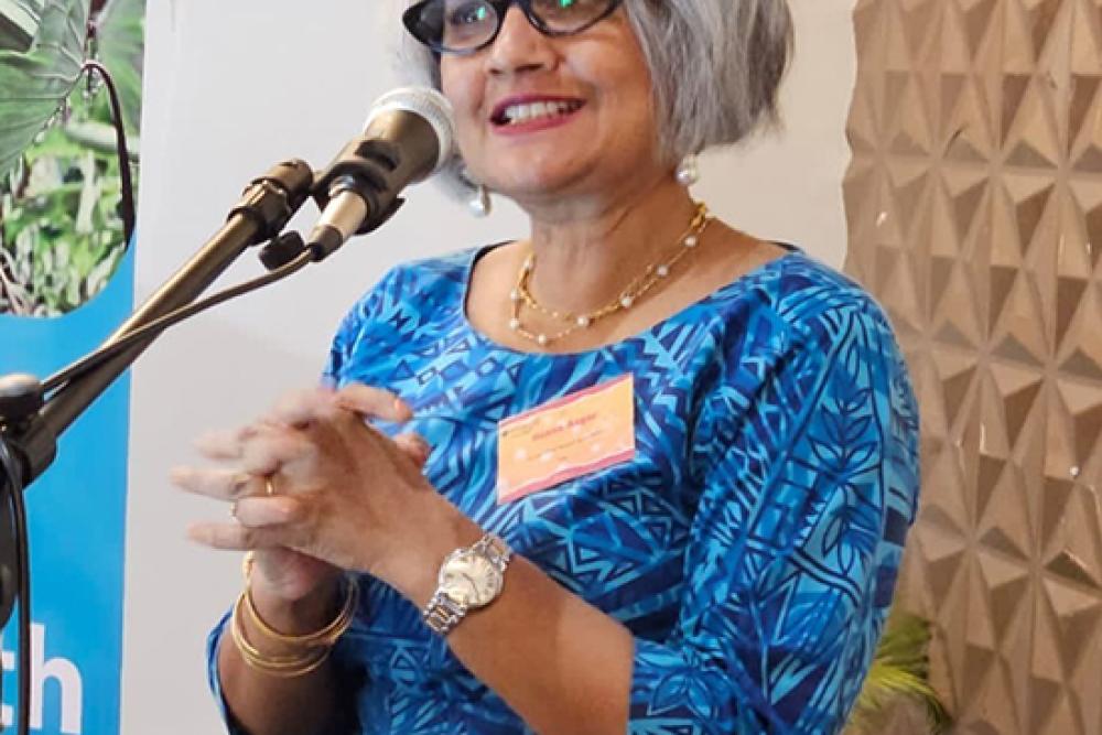 Dr. Raana standing at a microphone and podium presenting.