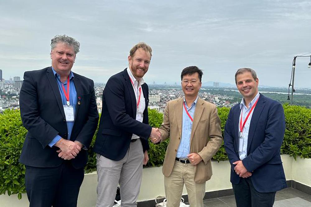 Four people standing, shaking hands, on a rooftop