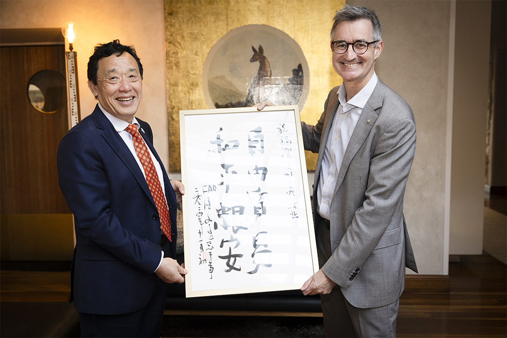 Image of two people standing together holding up a large piece of paper with writing on it